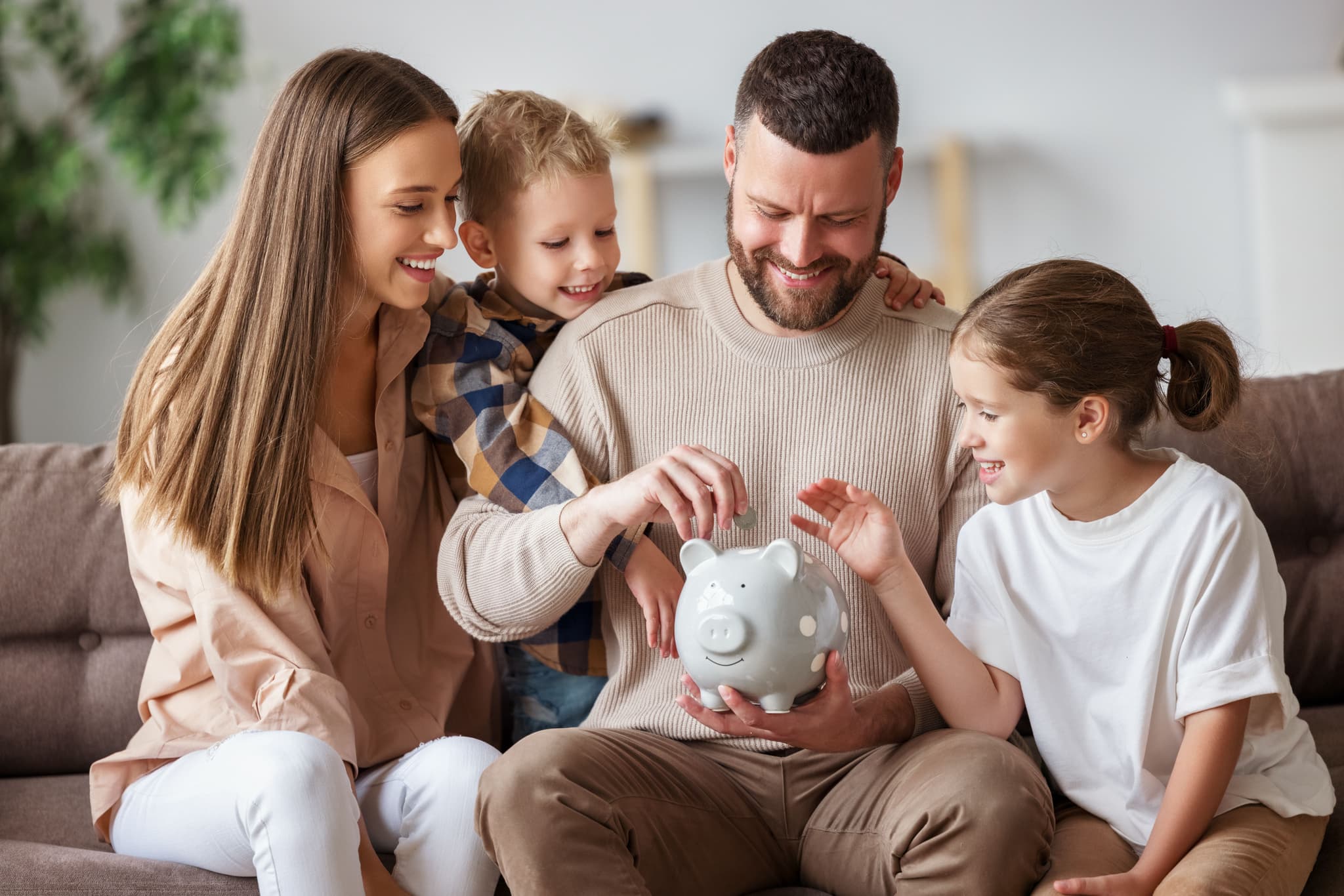 Family of four putting coins in to piggy bank