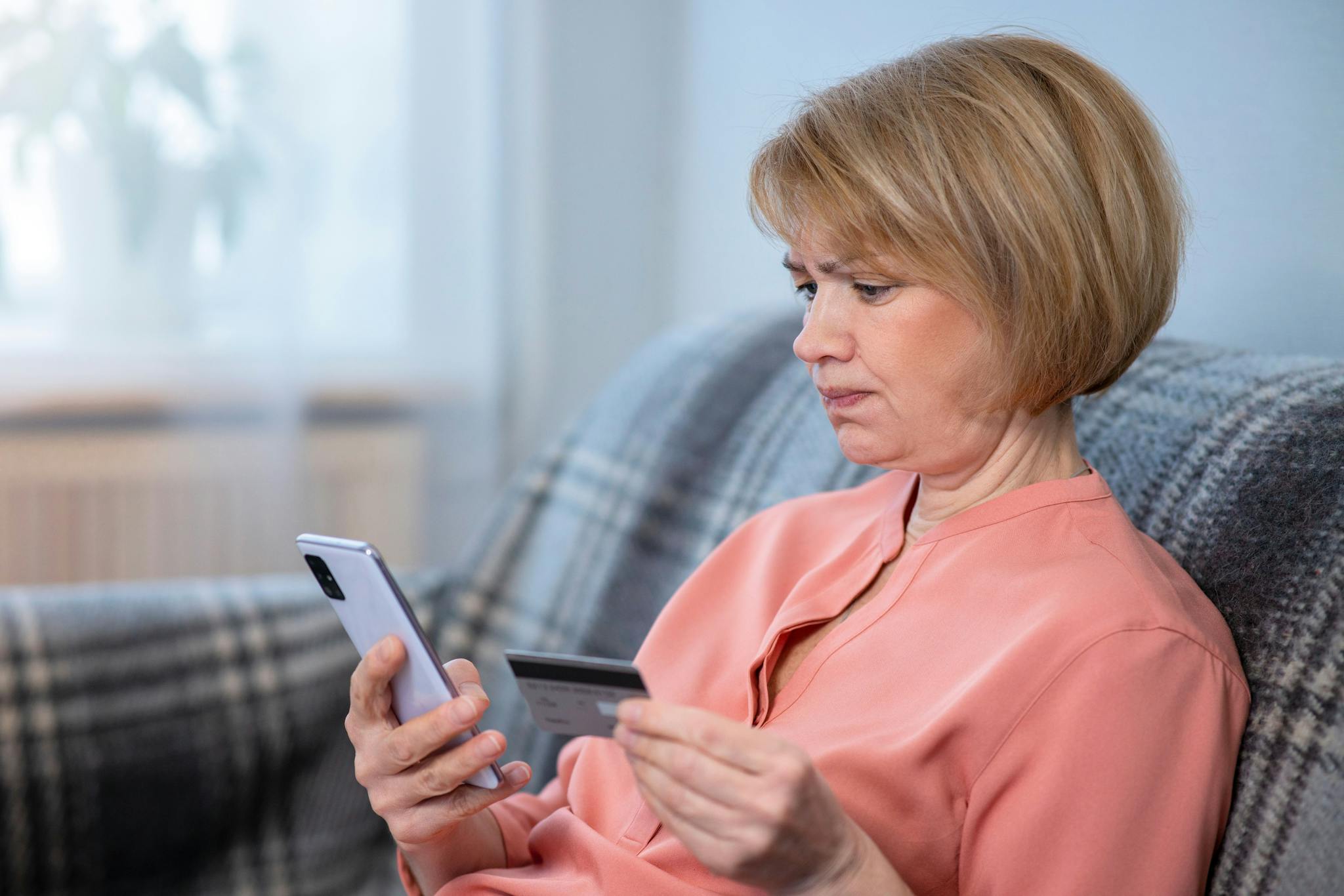 Women sitting on sofa adding her bank card details on her phone